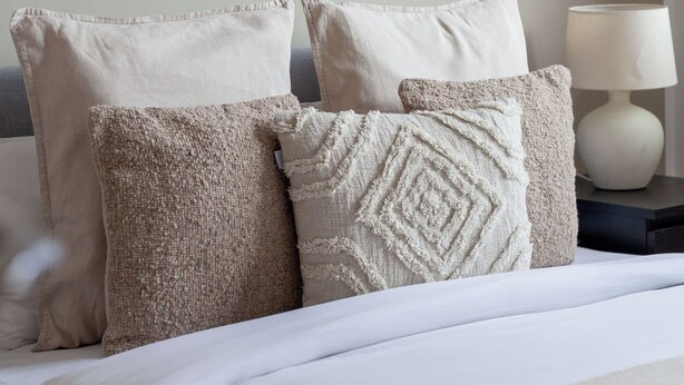 A neatly made bed with white bedding and three decorative pillows in a hotel room. - The Hackney Apartment (London)