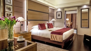 A hotel room with a bed, bedside tables, a lamp, a vase with flowers, a mirror, and a door leading to another room. - The Inn at the Spanish Steps Exclusive Collection - The Nest at The Spanish Steps (Rome)