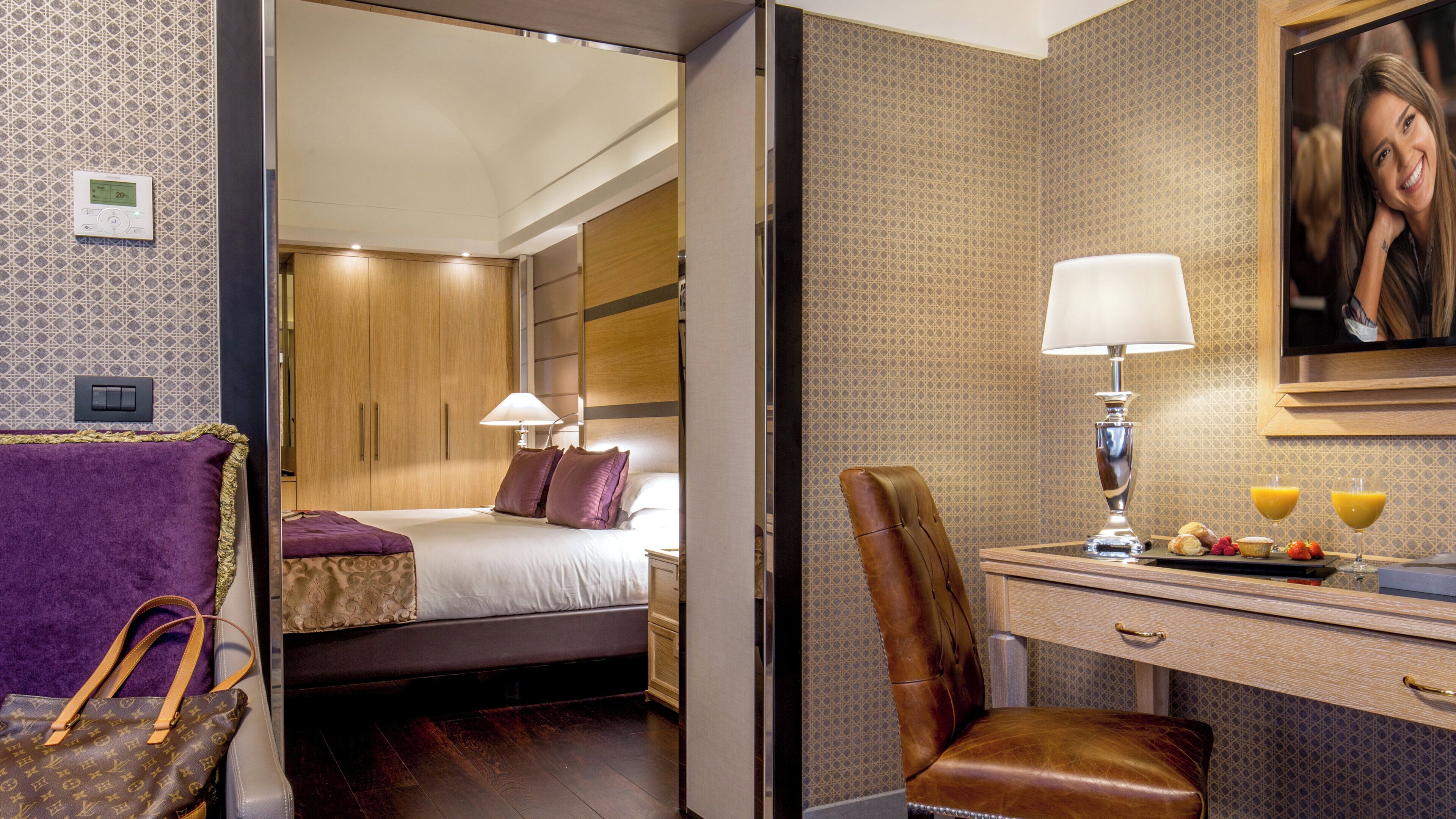 A hotel room with a bed, a desk with a lamp, a chair, and a breakfast tray.