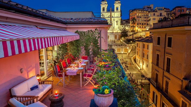A rooftop terrace with outdoor seating, a dining area, and a view of a historic church. - The Inn at the Spanish Steps Exclusive Collection - The Nest at The Spanish Steps (Rome)