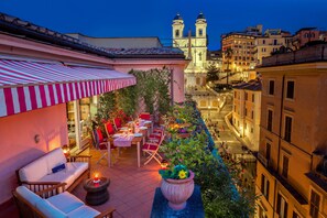 A rooftop terrace with outdoor seating, a dining area, and a view of a historic church. - The Inn at the Spanish Steps Exclusive Collection - The Nest at The Spanish Steps (Rome)