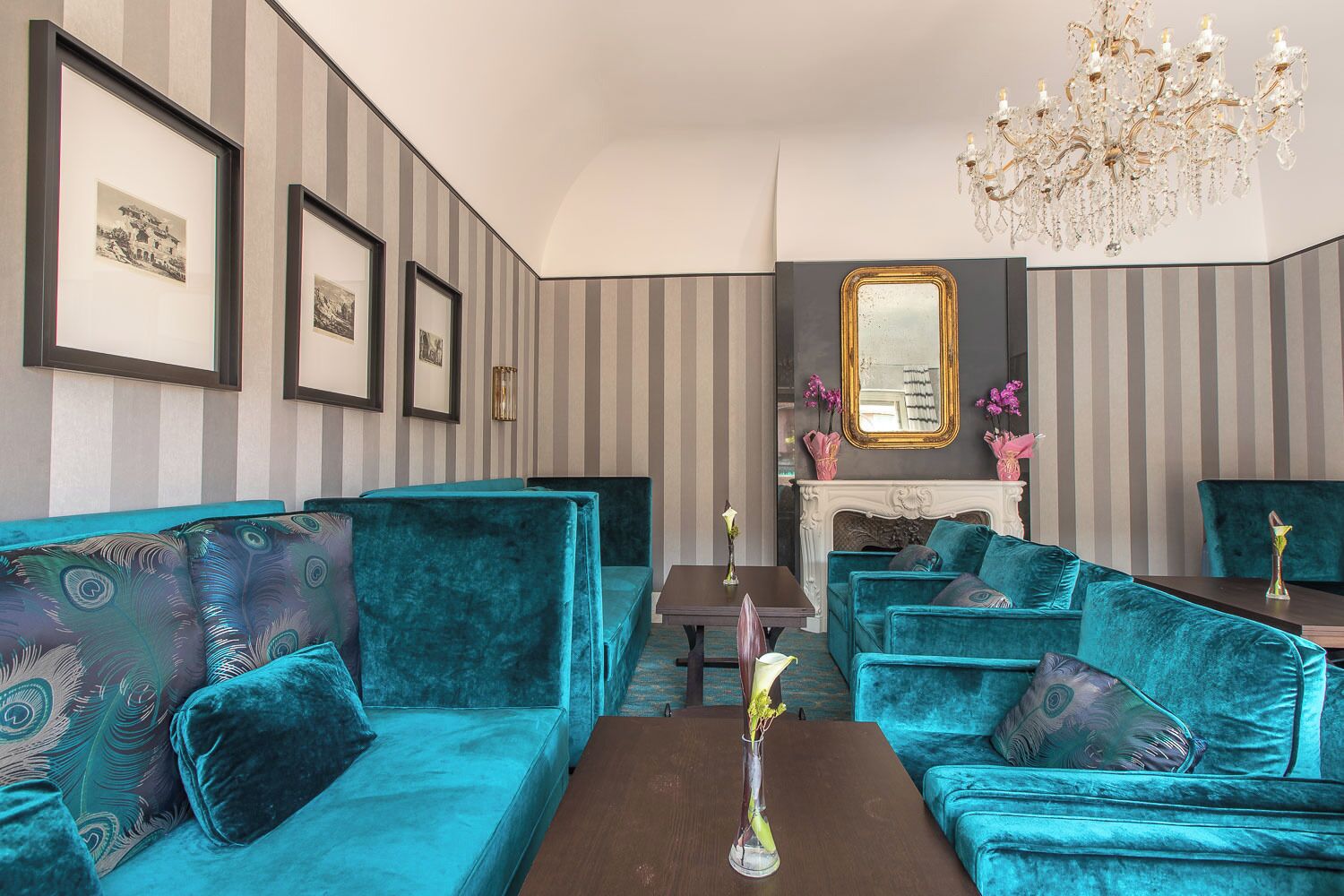 A room with teal upholstered sofas, a fireplace, and a chandelier.