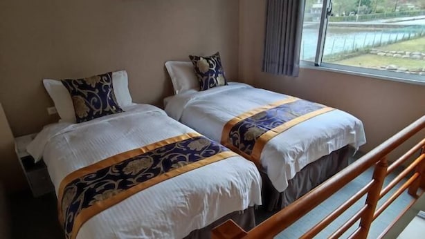 Une chambre d’hôtel avec deux lits, une rambarde en bois et une fenêtre donnant sur un plan d’eau.