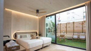 Una habitación de hotel moderna con una cama grande, una mesita y vistas al área exterior.