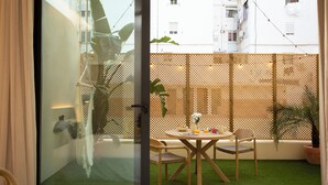 Un balcón con mesa, sillas y plantas en macetas.