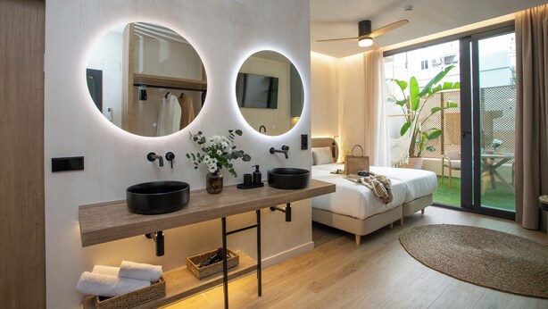 Un baño moderno con dos espejos grandes, un tocador de madera y un ventanal con vistas a un jardín.