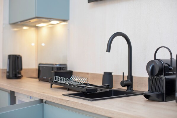 A modern kitchen with a black sink, a coffee machine, and a toaster on the counter. - Nomad Haux Mestalla (Valencia)
