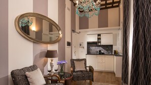 A living room with patterned sofas, a round coffee table, a mirror, and a chandelier. - The Inn at the Spanish Steps Prestige Collection - The Pearl (Rome)