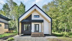 Ein modernes Haus mit Satteldach, einer Haustür und einem kleinen Fenster.