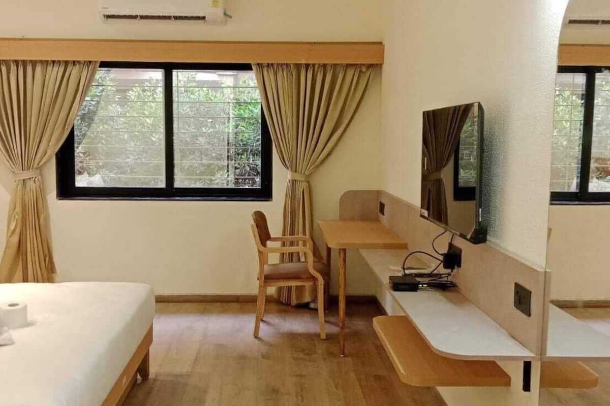 Ένα δωμάτιο ξενοδοχείου με ένα κρεβάτι, ένα γραφείο, μια καρέκλα και μια τηλεόραση.
