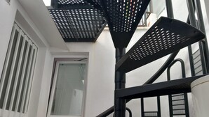 Un escalier en colimaçon en métal noir, avec une fenêtre en haut.