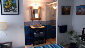 Une chambre à coucher comprenant un lit, une table de chevet, un miroir, un lavabo et une douche.