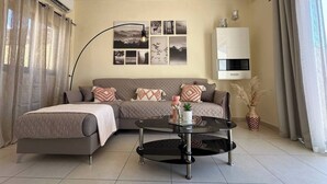 Ein modernes Wohnzimmer mit einer Eckcouch, einem Glastisch und einem an der Wand befestigten Fernseher.