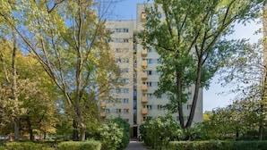 A multi-story residential building with a central entrance, surrounded by trees and a paved walkway. - Air-conditioned Apartment | Close to the Royal Baths (Warszawa)