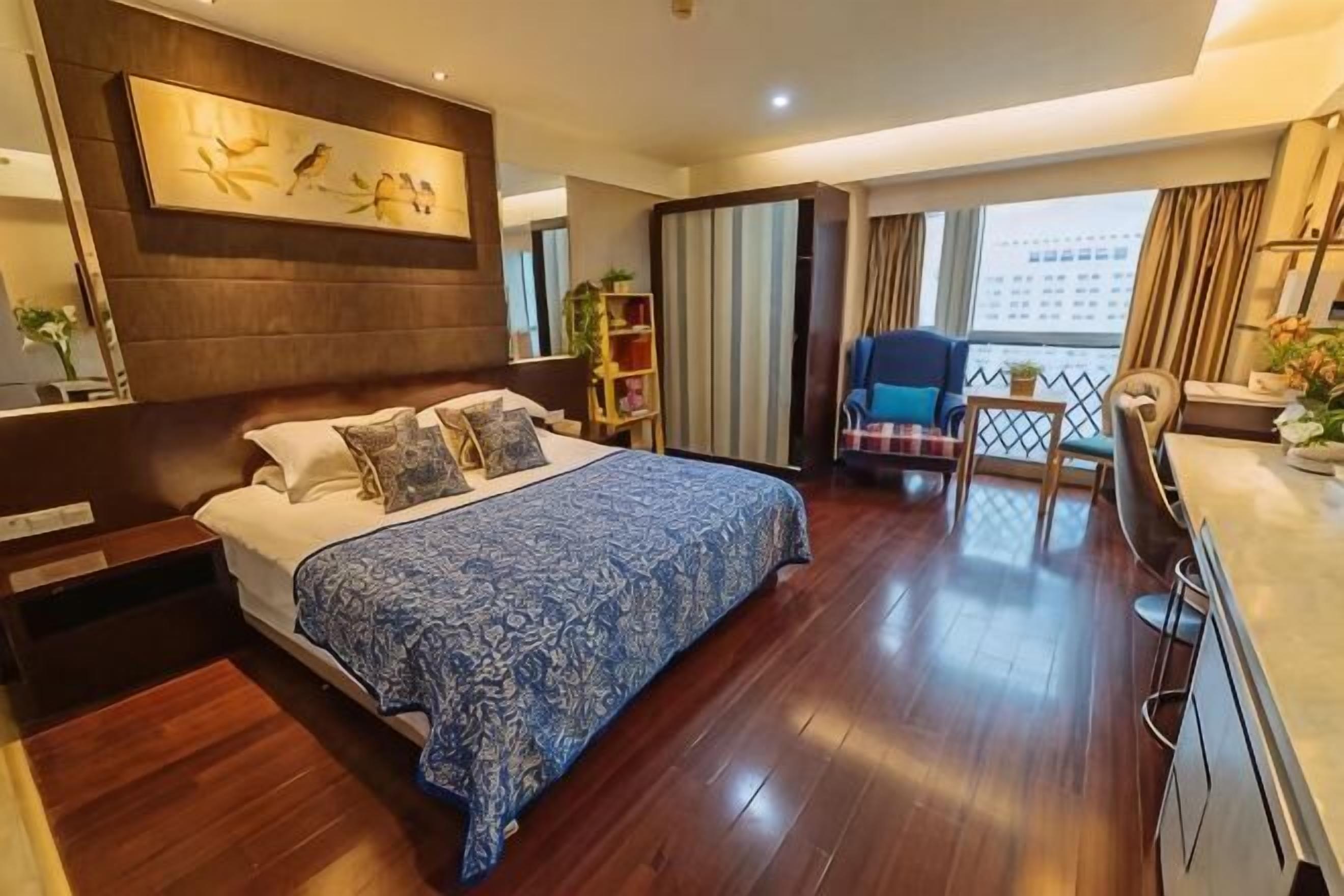 A modern hotel room with a large bed, a desk, a chair, and a balcony with curtains.
