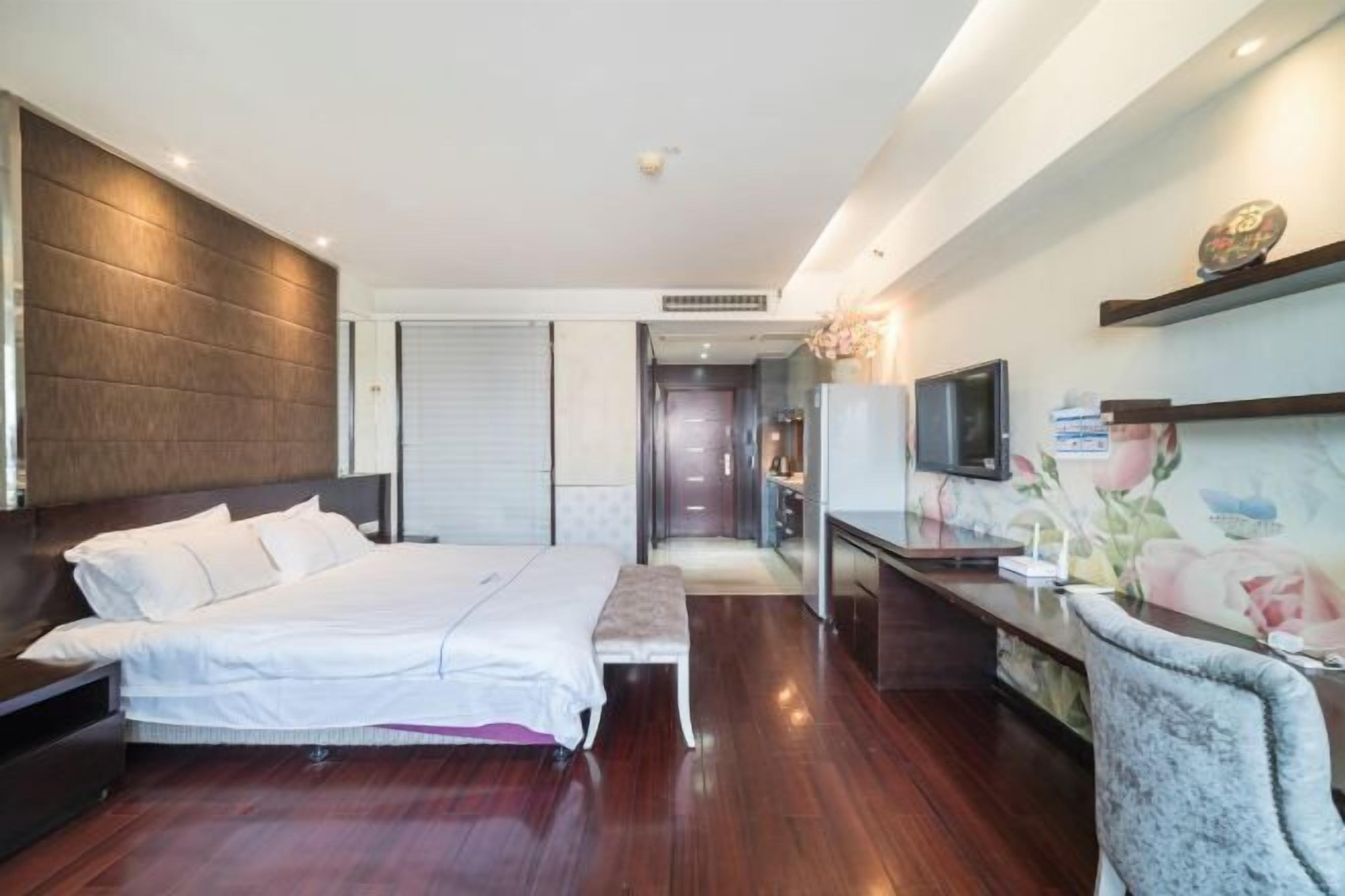 Habitación de hotel con cama, mesita de noche, televisor y escritorio con silla.