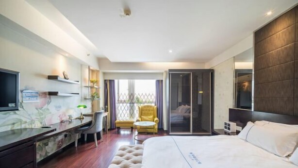 A hotel room with a bed, a desk, a chair, a TV, a sliding door, and a window. - City Tribe Apartment (Nanjing Kairun Jincheng) (Nanjing)