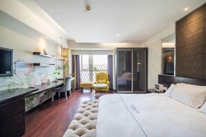 A hotel room with a bed, a desk, a chair, a TV, a sliding door, and a window.