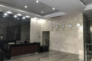 A hotel reception area with a marble floor, a reception desk, and a wall with clocks. - City Tribe Apartment (Nanjing Kairun Jincheng) (Nanjing)