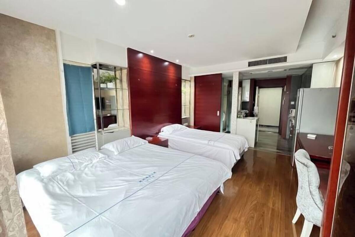 Habitación de hotel con dos camas, un escritorio, una silla y un espejo.