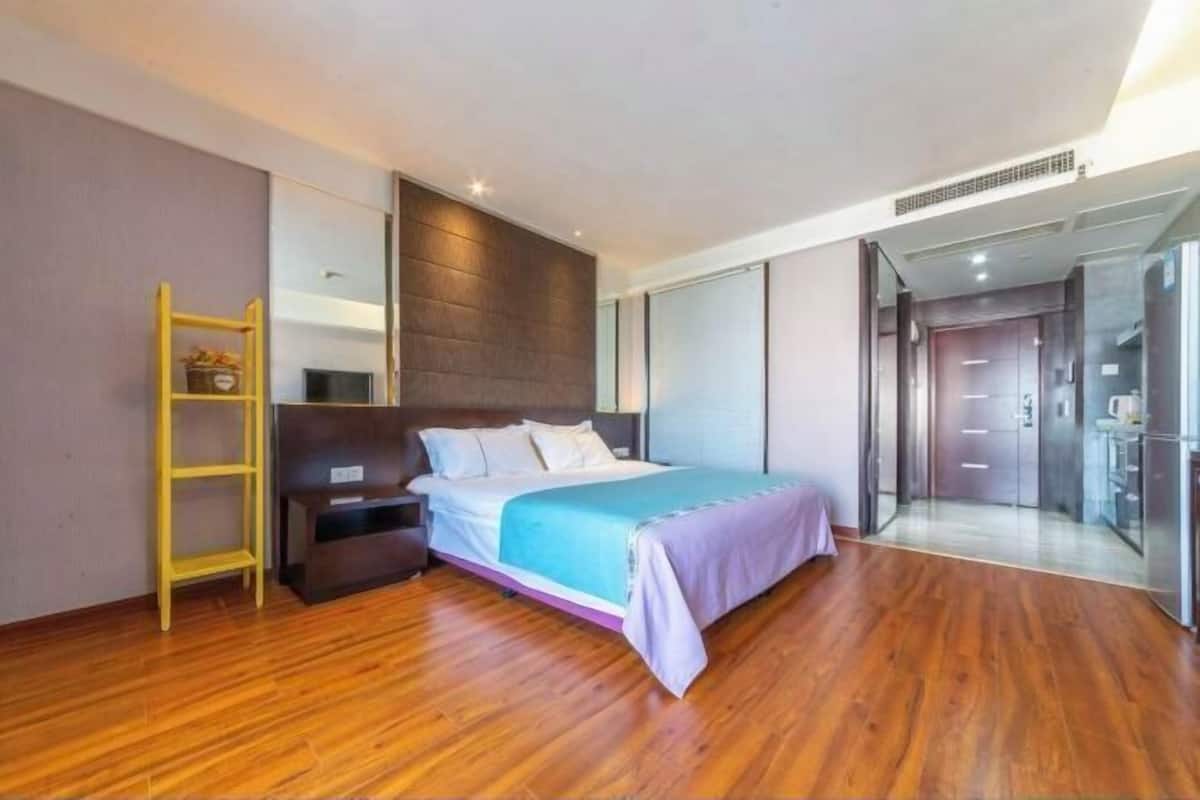 Un dormitorio moderno con cama, suelo de madera, una escalera amarilla y una puerta de vidrio que da a un baño.