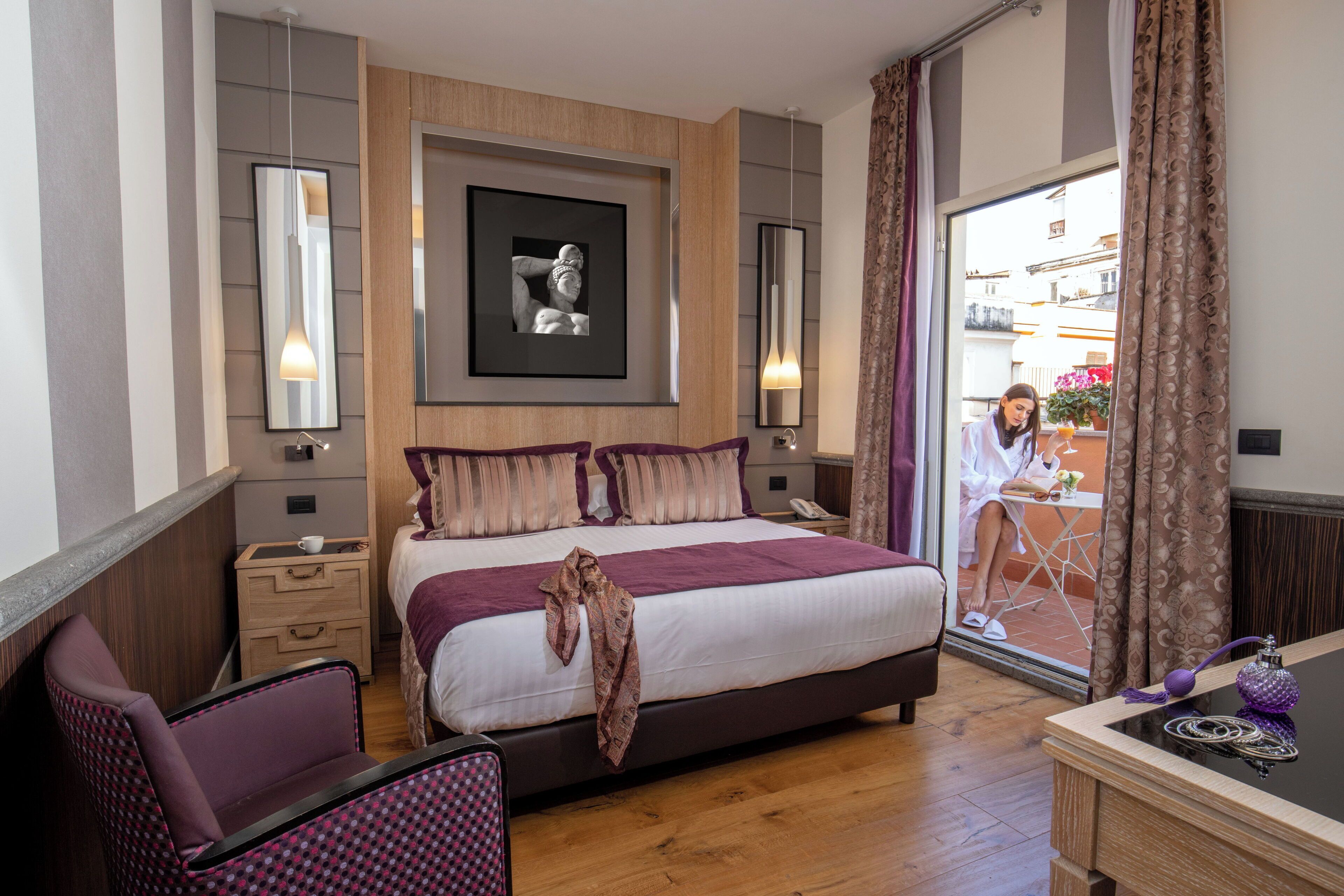 A modern hotel room with a large bed, a desk, and a view of the outside balcony.