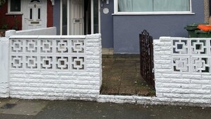 A two-story residential building with a white front gate, a small porch, and a number '5' on the wall. - 4 Beds, Sleeps 15, Near Lcy Airport & Excel London (London)