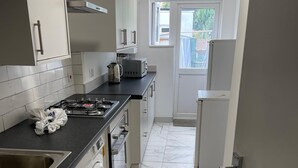 A kitchen with a washing machine, a sink, a stove, and a refrigerator. - 4 Beds, Sleeps 15, Near Lcy Airport & Excel London (London)