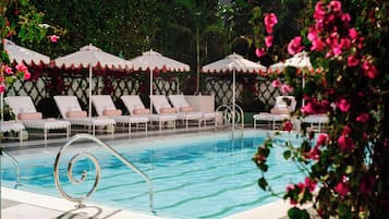 Una piscina al aire libre, sombrillas, sillones reclinables de piscina