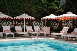 Una piscina al aire libre, sombrillas, sillones reclinables de piscina
