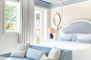 A bedroom with a bed, a nightstand, a lamp, a mirror, and a window with curtains.