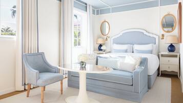 Een slaapkamer met een bed, een stoel, een tafel en een nachtkastje.