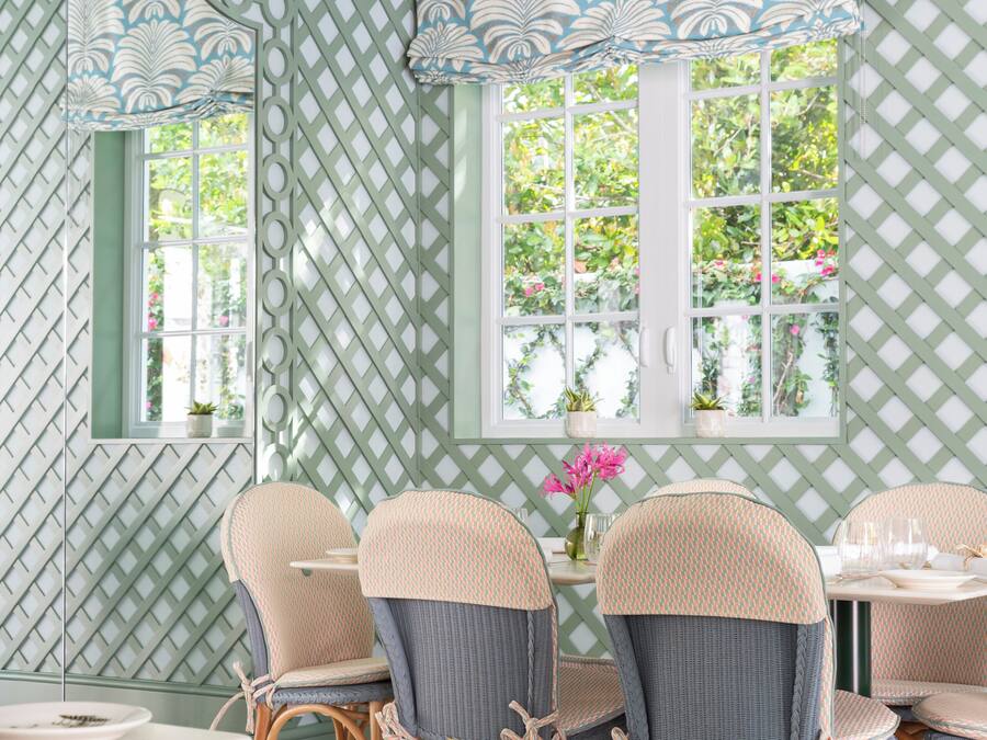 A dining area with wicker chairs, a table, and a window with a view of greenery.
