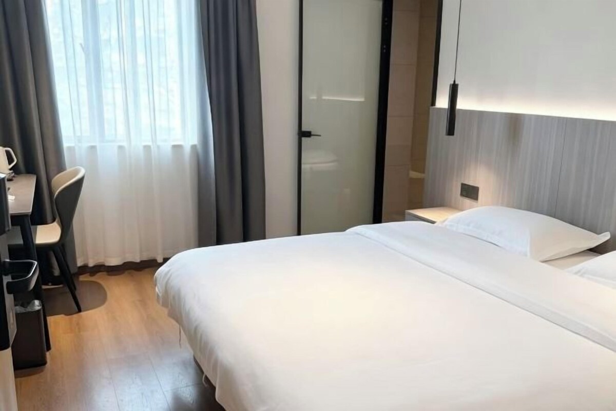 Une chambre d’hôtel comprenant un lit, une table de chevet, une lampe et un bureau avec une chaise.