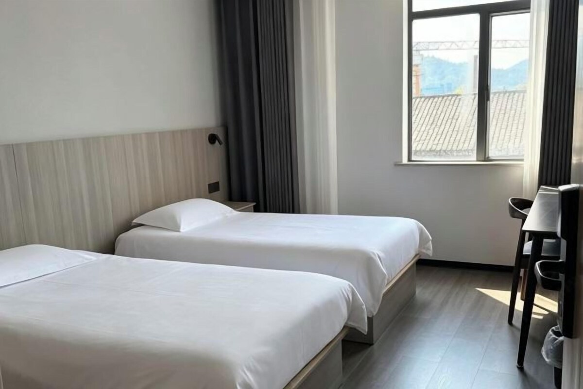 Une chambre d’hôtel avec deux lits, un bureau et une fenêtre donnant sur un beau paysage.