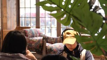 A room with patterned chairs, a large window, and a plant.