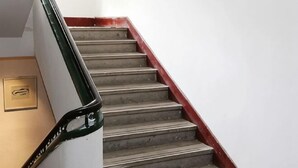 Eine Treppe mit roter Handlauf und weißer Wand.