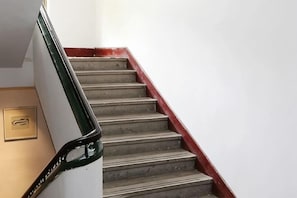 A staircase with a red handrail and a white wall.