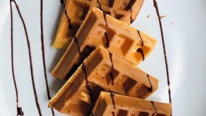 Une assiette de gaufres nappées de sirop au chocolat et décorée d’une feuille de menthe.