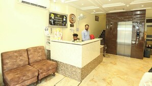 A hotel reception area with a marble reception desk, a clock, a calendar, and a sofa. - HOTEL TRADITION (Amritsar)