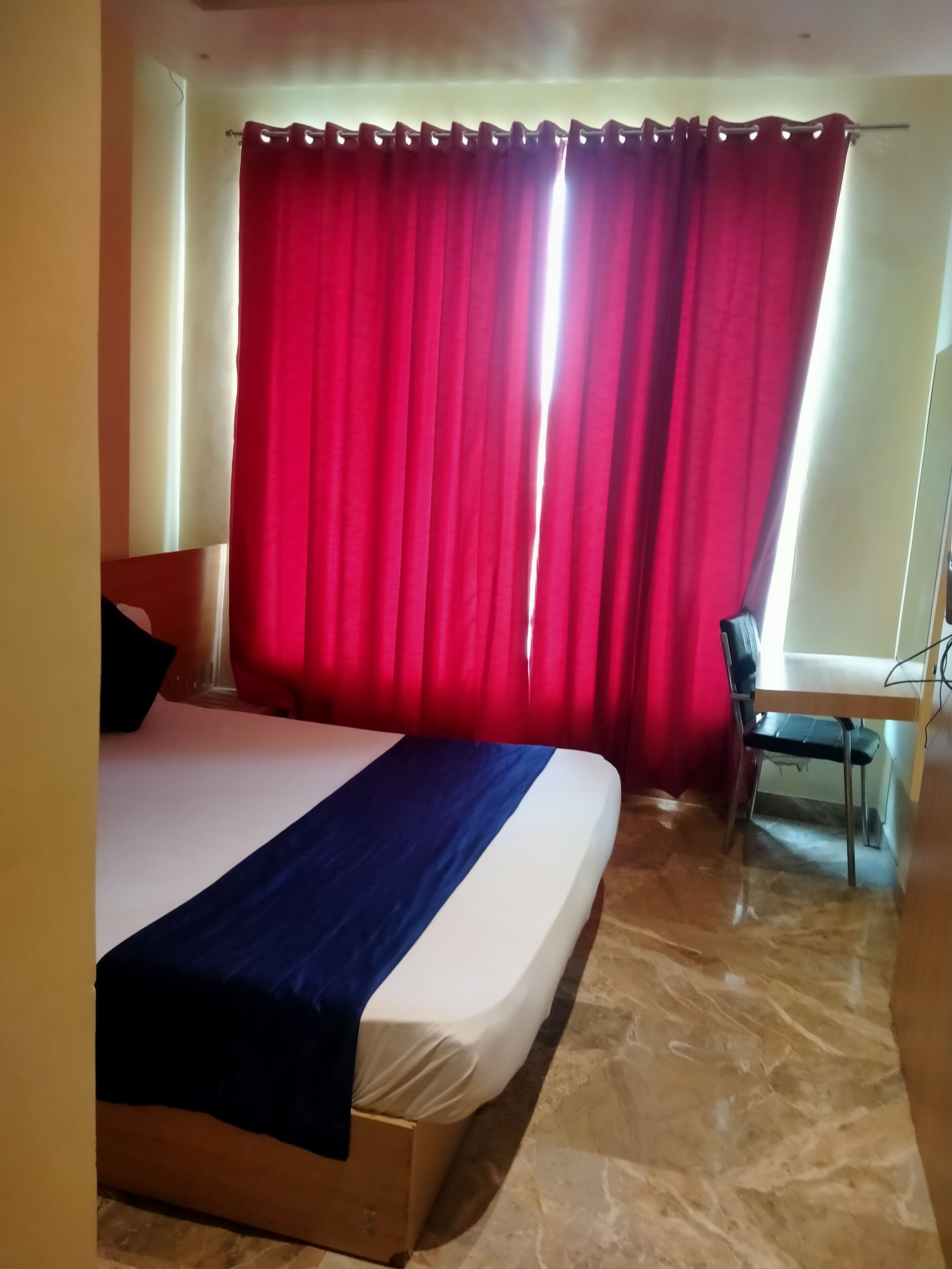 A hotel room with a bed, a desk, and a chair.