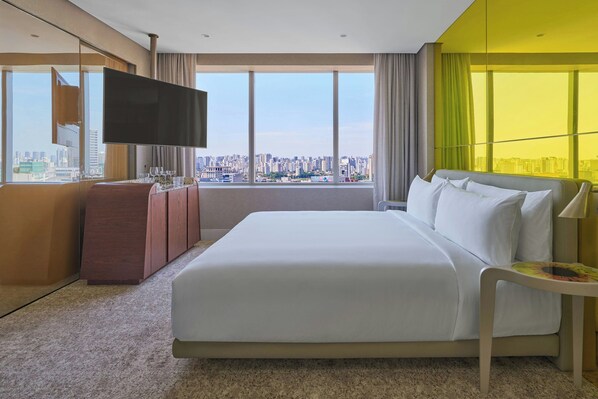 Una habitación de hotel moderna con una cama grande, televisión y vistas a la ciudad.