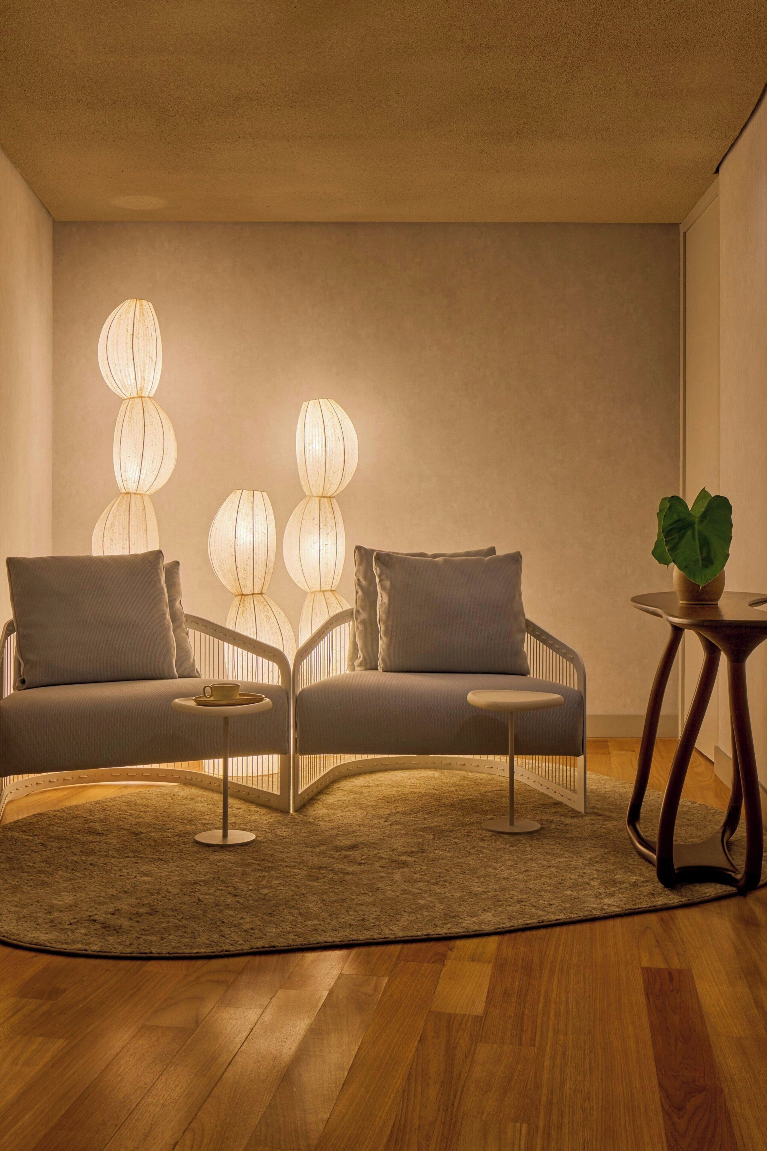 Un salon moderne avec un canapé, deux tables d’appoint et une plante en pot.