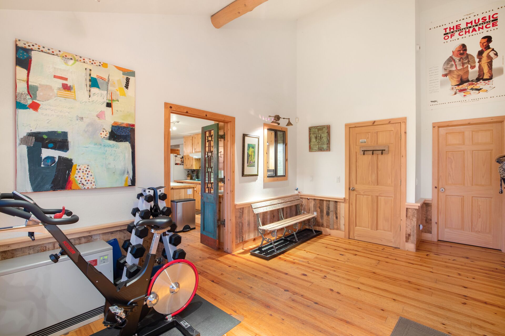 A gym with exercise equipment, wooden floors, a mirror, and a poster on the wall.