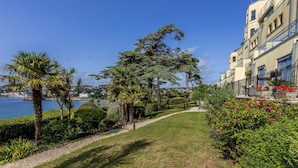 Un hotel sulla costa con vista sul mare, un giardino curato e un edificio con balconi.