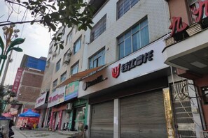 Une vue de rue avec des devantures de magasins fermées, notamment un bâtiment doté d’un grand portail de garage et d’une enseigne indiquant le nom d’une entreprise.