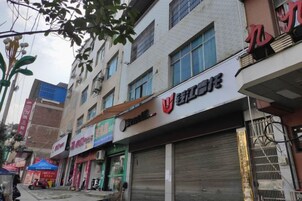 Vista de calle con comercios cerrados, incluyendo un edificio con una gran puerta de garaje y señalización de un negocio.