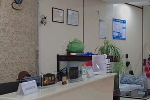 Una recepción con un cartel, una planta y un aviso en la pared.