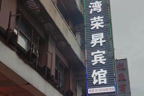 A building with a sign that reads 'Bingling' and a phone number. - Jiujiu Express Hotel (Dejiang)