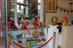 Exhibición de varios productos en estantes con lazos rojos, un mostrador blanco y un adorno sobre un pedestal.
